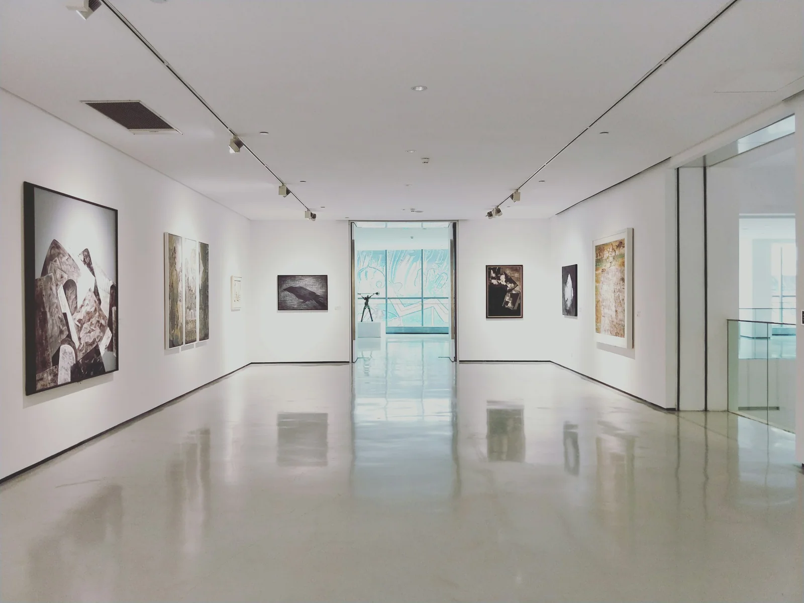 Light-filled art gallery with framed paintings and a polished floor