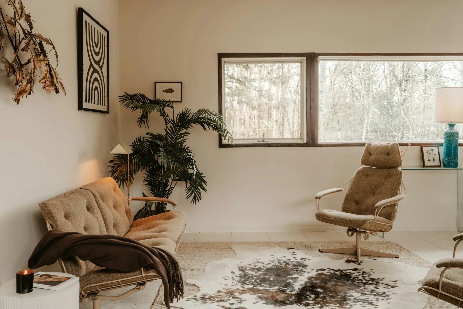Sunlit vintage interior with sculptural lounge chairs, framed art and natural textures