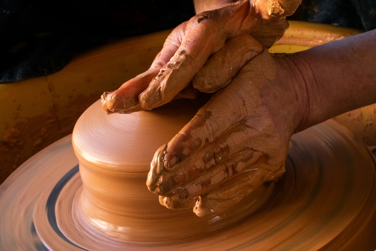 An artisan shaping terracotta clay by hand on a pottery wheel